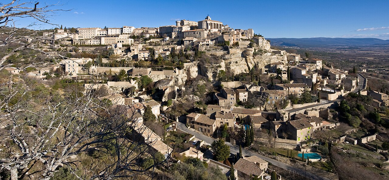 Le village perché de Gordes au coucher du soleil, maisons de pierre dorée étagées sur la colline, dans le Luberon en Provence
